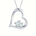 Detail of a silver-tone heart pendant necklace with a small turtle in white fire opal - White