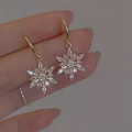 Exquisite goldene Schneeflocken-Ohrhänger mit funkelnden Kristallen in der Hand - Schneeflocken Ohrringe