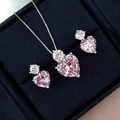 Nahaufnahme von rosa Herz-Halskette und Ohrringen in einer blauen Samtbox - Rosa