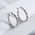 Minimalist 925 sterling silver hoop earrings with twisted metal texture on a white book - Silver