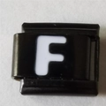 Macrodetail van een Italiaanse armbandmodule met witte letter F op zwart roestvrij staal - Zwart En Wit Letter F (1220)