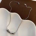 Minimalist silver snake chain necklace with a liquid metal bean pendant on a ceramic plate - Silver