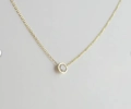 Detailed close-up of a delicate gold-plated clavicle chain with a bezel-set zircon pendant - Gold