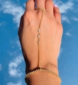 Detail showing gold hand chain ring with white zircon accents on hand with blue sky background - Gold Bead with Three Stones Style (Gold D)