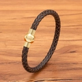 Geflochtenes dunkelbraunes Lederarmband mit goldenem Magnetverschluss auf Holzhintergrund - 19cm / Brauner Riemen Goldene Schnalle