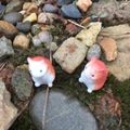 Zwei orange-weiße Hamsterfiguren aus Harz auf Moos und Naturstein-Landschaft - Orange