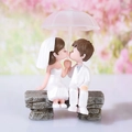 Miniatur Hochzeitsfiguren auf einer Bank mit rosa Regenschirm als Tischdeko - Weiß / Weiß