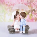 Miniatur-Küssen-Hochzeitspaar-Figuren mit weißem Regenschirm auf grauer Bank - Blau & Weiß / Blau