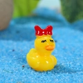 Statuina di anatra gialla in resina con fiocco rosso e ciglia su sabbia blu - Stile Con Fiocco (Giallo Ragazza)