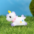 Miniature white and lavender resin unicorn figurine lying on green grass landscape - Purple