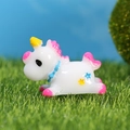 Cute miniature white unicorn figurine with pink mane and blue collar on green grass - Rose Red