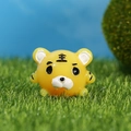 Niedliche runde Tiger-Resin-Figur als Miniatur auf grünem Gras unter blauem Himmel - Tiger / Gelb