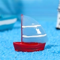 Miniatur Segelschiff aus Harz mit rotem Rumpf und blau gestreiften Segeln auf blauem Sand - Mittel / Blau