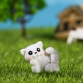 Miniatur-Katzenfigur aus Harz mit grauen Streifen in einer grünen Gartenlandschaft - Seitlich Liegend Verspielt Stil