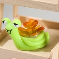Cute green cartoon snail figurine with orange succulent shell on a wooden stand - Green