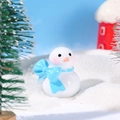 Miniature snowman figurine with blue bow scarf and orange nose on faux snow - Snowman with Blue Bow