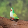Miniature green kingfisher bird figurine with white belly on a wooden branch - Green