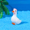 Miniature white resin swan wearing a pink sun hat with bow on blue decorative sand - Head Up With Pink Hat Style (A)