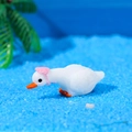 Miniature white swan figurine with a pink hat and orange beak on blue sand - Lying Posure With Pink Hat Style (C)