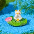Miniatura de rana de resina blanca sobre una hoja de loto verde con pequeña flor rosa - Estilo D
