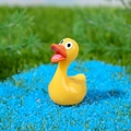 Miniatuur gele hars eend op blauw zand voor decoratie van succulentenlandschap - Rubber Eend