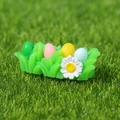 Miniatura de nido de Pascua en resina con cuatro huevos macaron y una pequeña margarita - Huevos de Pascua Sobre Hierba Verde