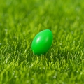 Bright green resin Easter egg figurine ornament placed on natural green grass - Green Easter Egg