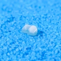 Translucent white resin crown tooth model placed on vibrant blue sand background - Mini Crushed Ice (Style L)