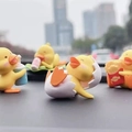 Gros plan de quatre figurines de canard jaune mignonnes en diverses poses pour voiture - Ensemble Jaune