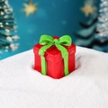 Miniatur Weihnachtsgeschenkbox in Rot mit grüner Schleife auf verschneiter Landschaft - Rote Geschenkbox