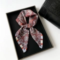 Detail eines Satin-Halstuchs mit Paisley-Muster in Rostrot und Beige in einer Box - 70*70cm / Rot