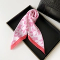 Detail of pink geometric silk scarf draped over a minimalist black tray and handbag - Pink