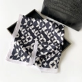 Elegant satin scarf with black and white geometric pattern next to a black leather handbag - Black and White