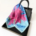 Detailed shot of floral print silk scarf with large pink flowers draped on a handbag - 70cmx70cm / Blue