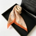 Seidenschal mit Blumenmuster in Orange und Beige, elegant auf schwarzem Tablett gefaltet - Orange
