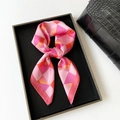Pink and orange geometric silk scarf displayed in a black box with luxury handbag - Pink