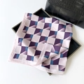 Elegant geometric silk scarf with purple and blue tones folded on a fashion bag - Purple