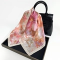 Silk scarf with pink floral print tied elegantly on black faux leather handbag handle - Pink