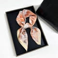 Elegant floral silk scarf in orange and beige tones tied in a decorative bow - Orange