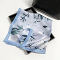 Elegante lichtblauwe satijnen sjaal met magnoliaprint op een zwart dienblad - Blauw