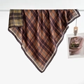 Detail of a large square scarf with brown and orange plaid patterns on a white hanger - Color 6