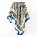 Detail of satin paisley scarf showing blue and yellow patterns on a white display block - 90x90cm / Blue