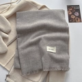 Solid gray winter scarf with fringe detail and woven label on a beige jacket - Silver Gray