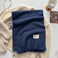 Navy blue herringbone scarf with fringe edges and brand label on a cozy winter backdrop - Navy Blue