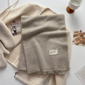 Elegant taupe winter scarf with tassels and brand tag on cream fleece coat background - Light Gray