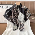 Detail of silk scarf with leopard print and floral design hanging on a wooden hanger - Color 16