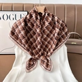 Detailed close-up of a brown houndstooth silk scarf on a wooden hanger with a white dress - Color 18