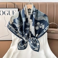 Detail view of navy blue silk scarf with white floral patterns on a wooden hanger - Color 36