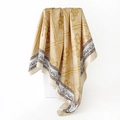 Detail of golden paisley pattern silk scarf showing drape and smooth glossy texture - 90x90cm (D9496) / Yellow