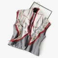 Detail of vintage paisley silk scarf tied on a grey vest against a white background - Orange Paisley